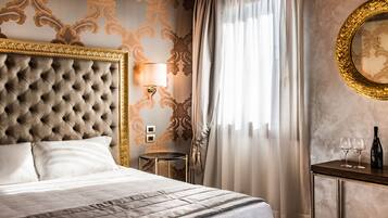 A luxurious hotel room with a tufted headboard, a bedside table with a lamp, a small round table, and a mirror on the wall.