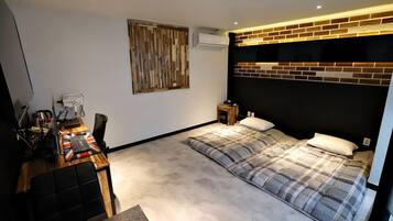 A bedroom with a bed, a desk with a computer, a chair, and a wall-mounted air conditioner.