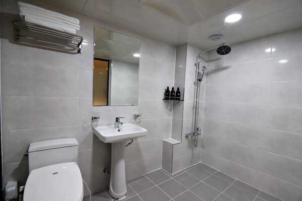 A modern bathroom with a toilet, sink, mirror, and shower.