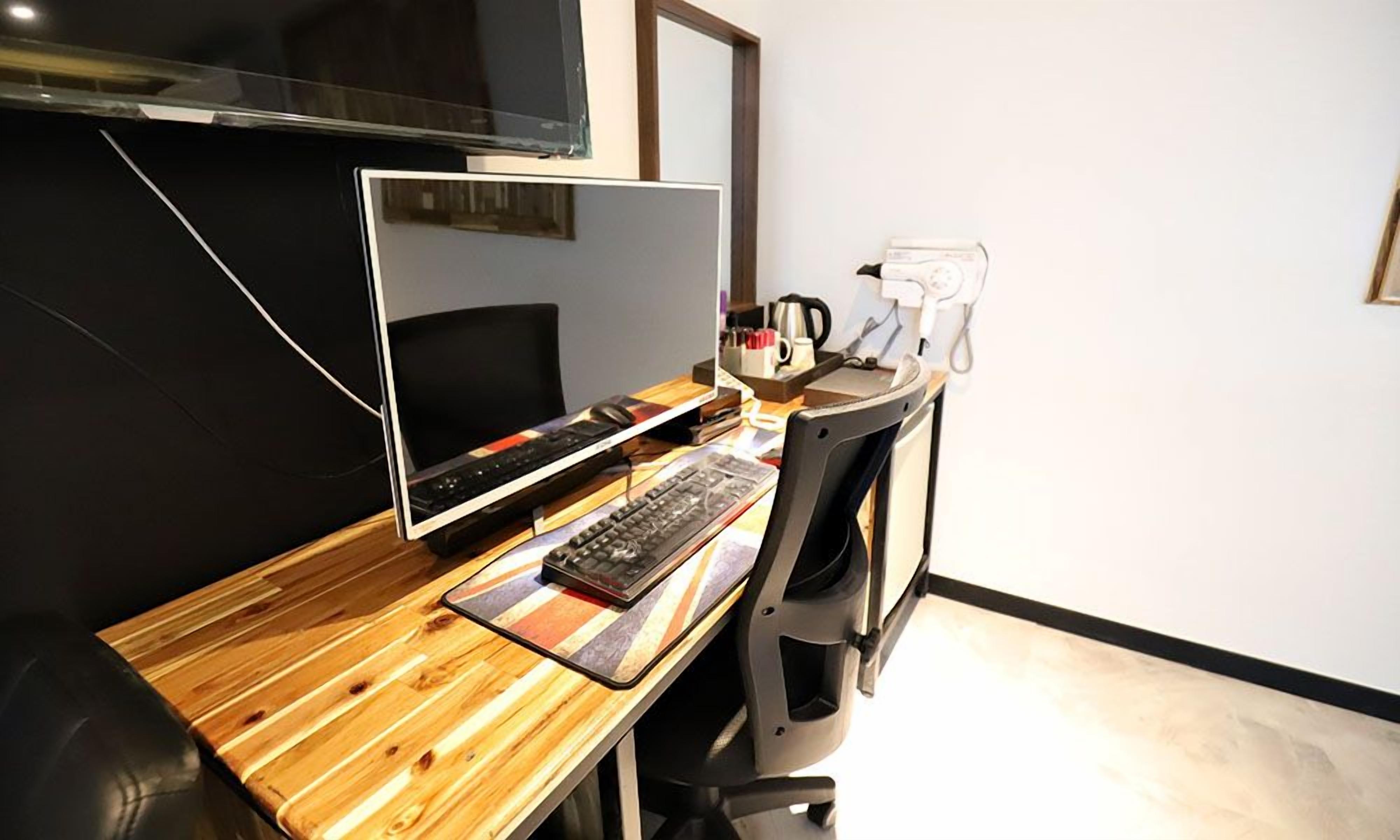 A workspace with a computer, keyboard, and mouse on a wooden desk.