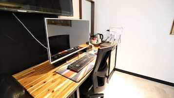 A workspace with a computer, keyboard, and mouse on a wooden desk.