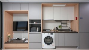 Cocina compacta con lavadora, microondas y una pequeña encimera.