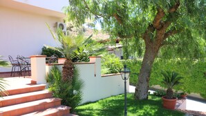 A set of outdoor stairs leading to a patio area with a white wall, a palm tree, and a lamp post. - B&B La Piccola Oasi (Motta San Giovanni)