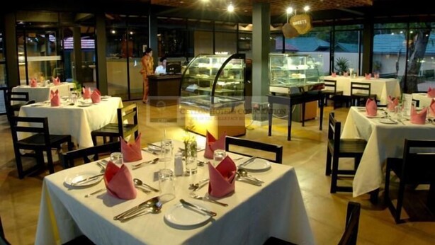 A restaurant with tables set for dining, a dessert display case, and a view of the outside. - Heritage Habarana Resort (Habarana)