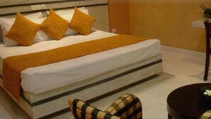 A bed with a white mattress, a brown blanket, and three pillows. - Heritage Habarana Resort (Habarana)