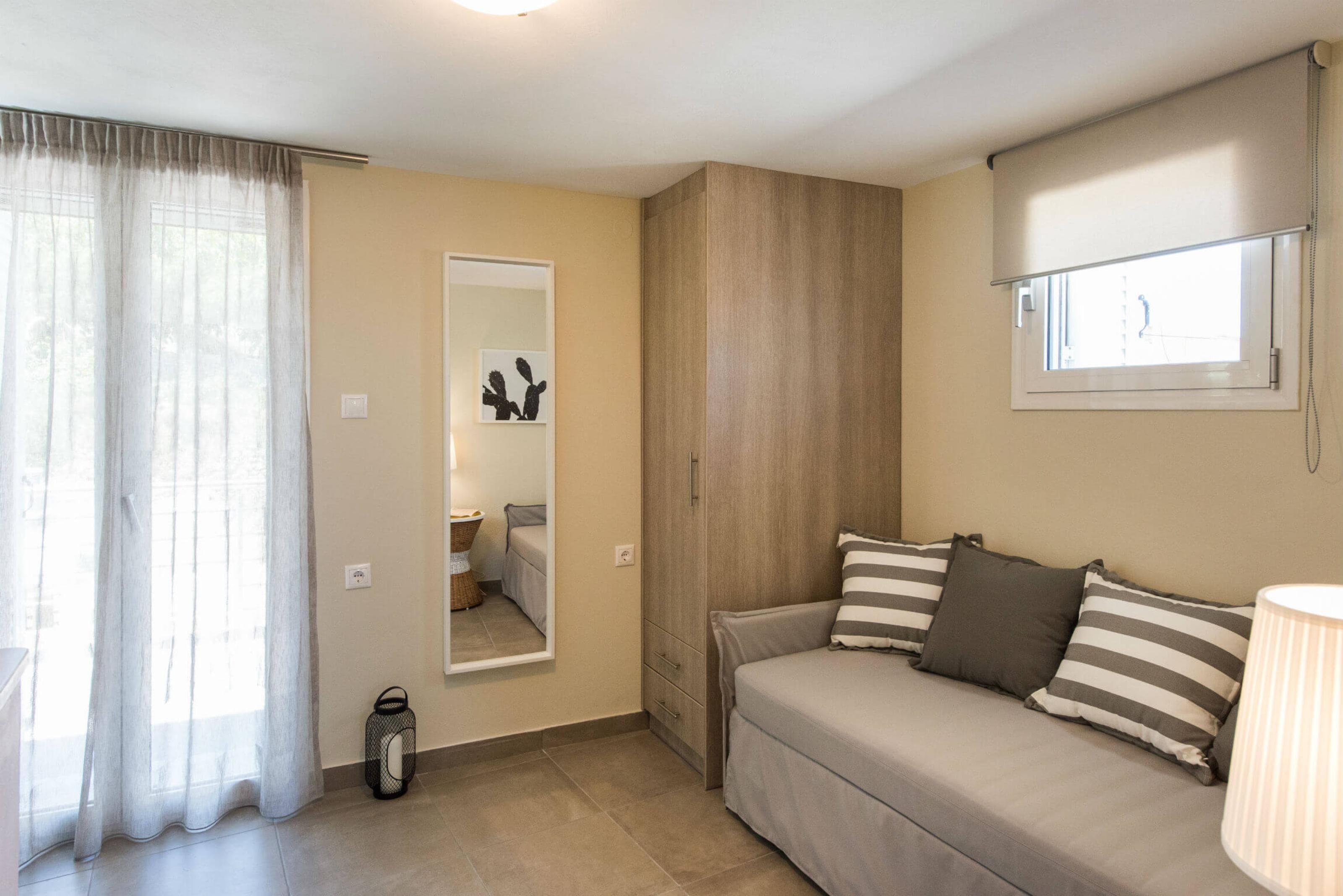 A bedroom with a bed, a wardrobe, a window with a view, and a lamp.