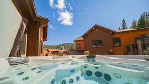 Een jacuzzi met uitzicht op een houten gebouw en bergen op de achtergrond.