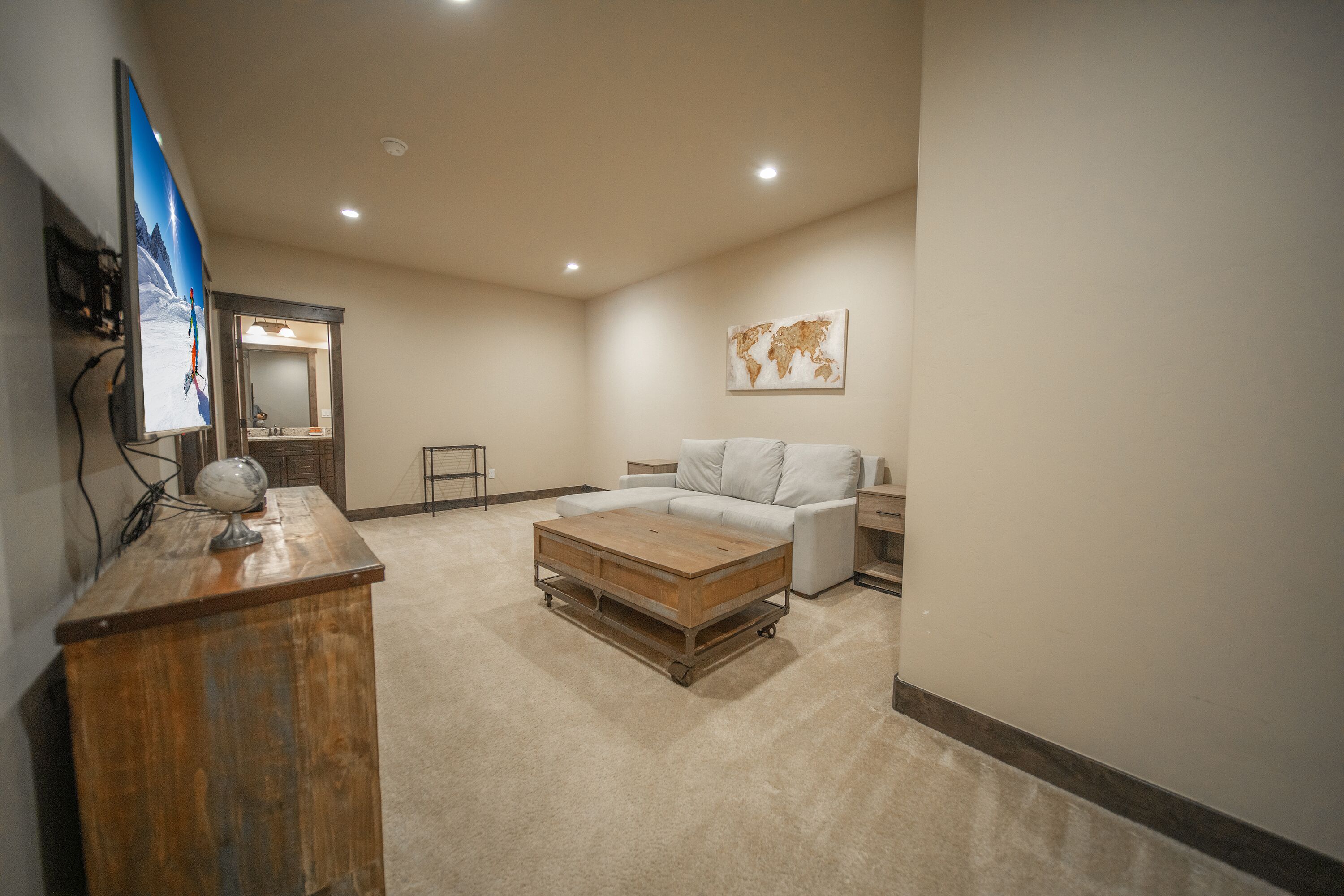 A spacious room with a large bed, a wooden coffee table, a globe, and a world map on the wall.