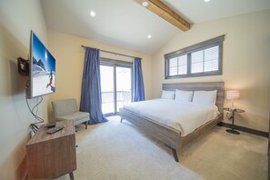 A bedroom with a large bed, a chair, a desk, a TV, and a window with curtains. - Alders 24 Outpost Dr (Keystone)
