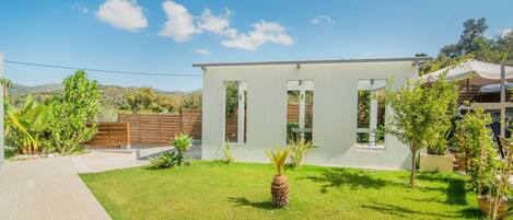 A modern house with a well-maintained lawn, a wooden fence, and a clear blue sky.