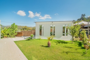 A modern house with a well-maintained lawn, a wooden fence, and a clear blue sky.