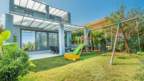 A modern house with a patio, a swing set, and a slide. - Villa Alyona  (Platanias)