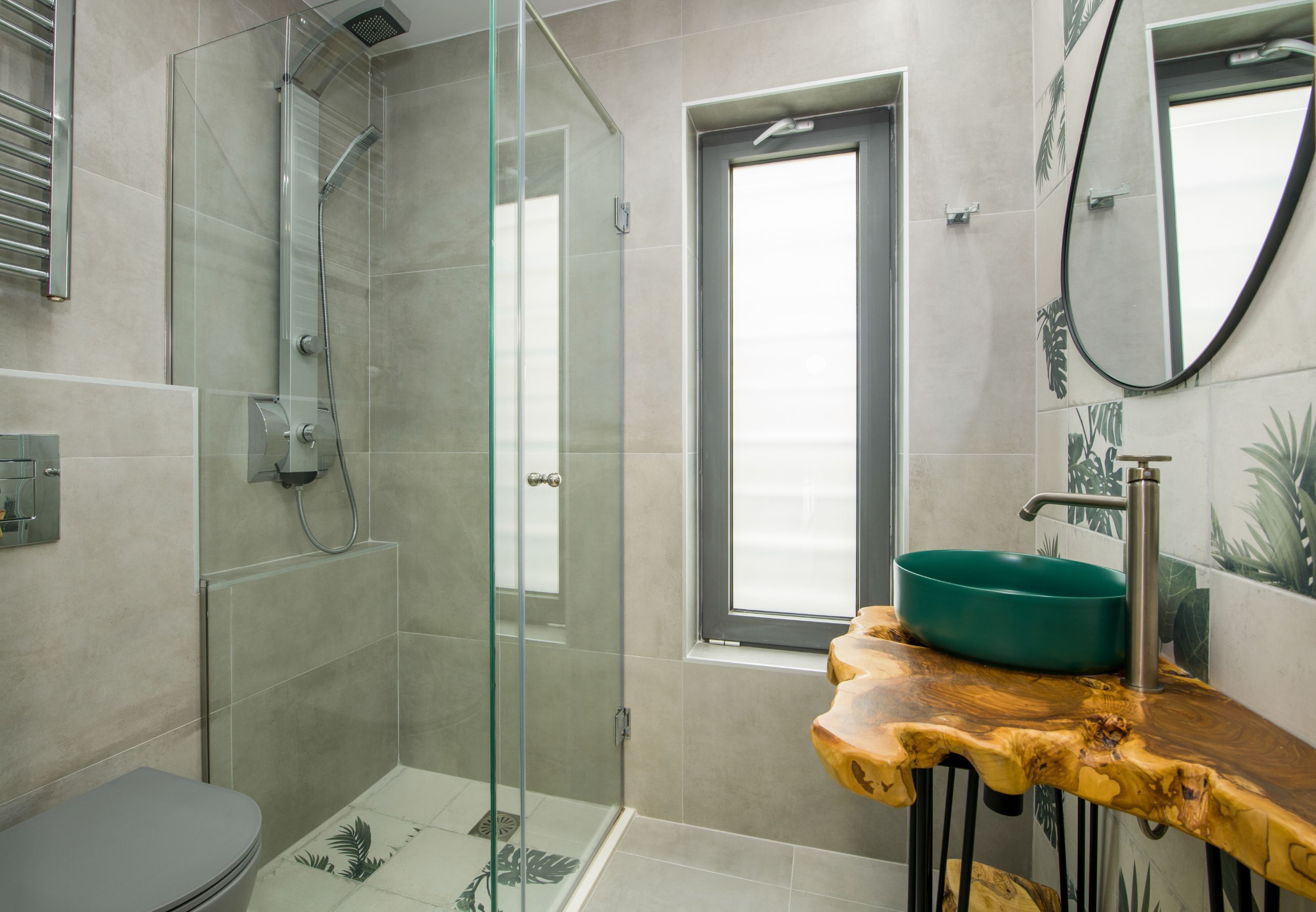 Une salle de bain moderne avec une douche à parois de verre, un meuble-lavabo en bois avec un vasque verte et un grand miroir.