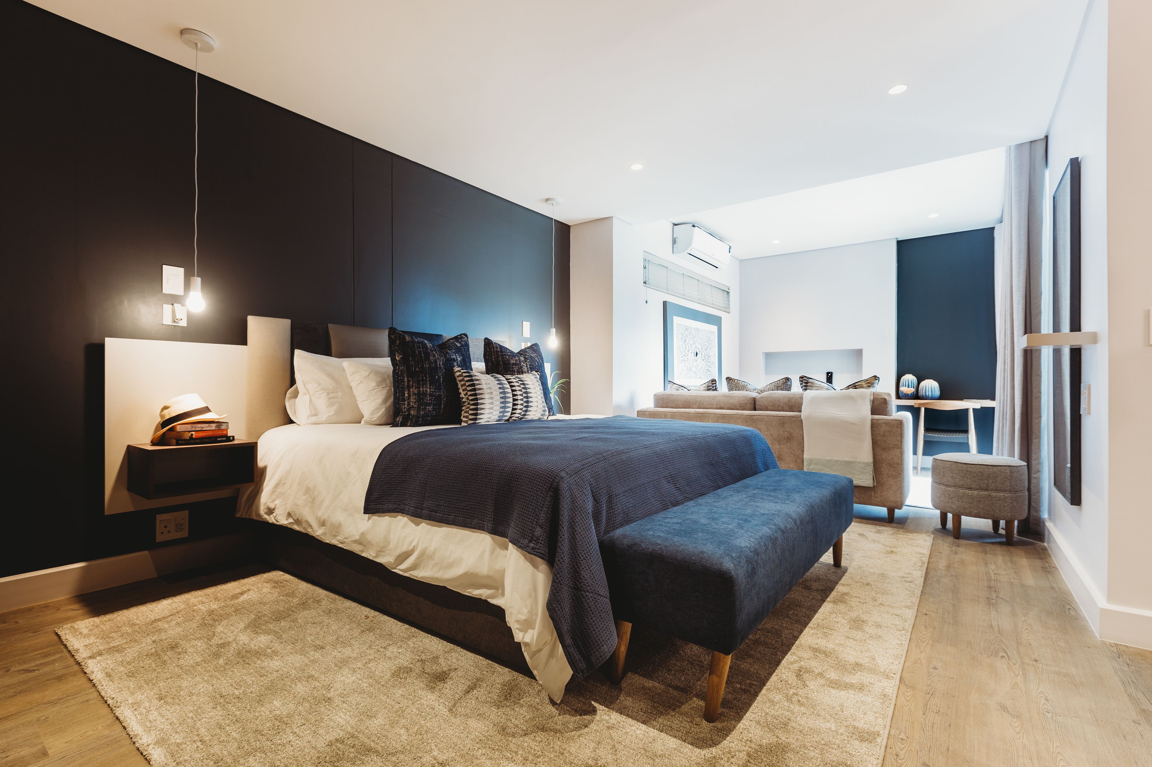 Quarto moderno com uma cama grande, mesas de cabeceira e um espaço para escritório.