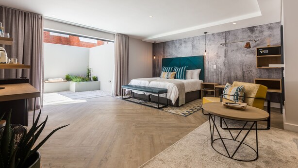A modern bedroom with a large bed, a desk, and a view of the outside. - The Junction Boutique Hotel (Plettenberg Bay)