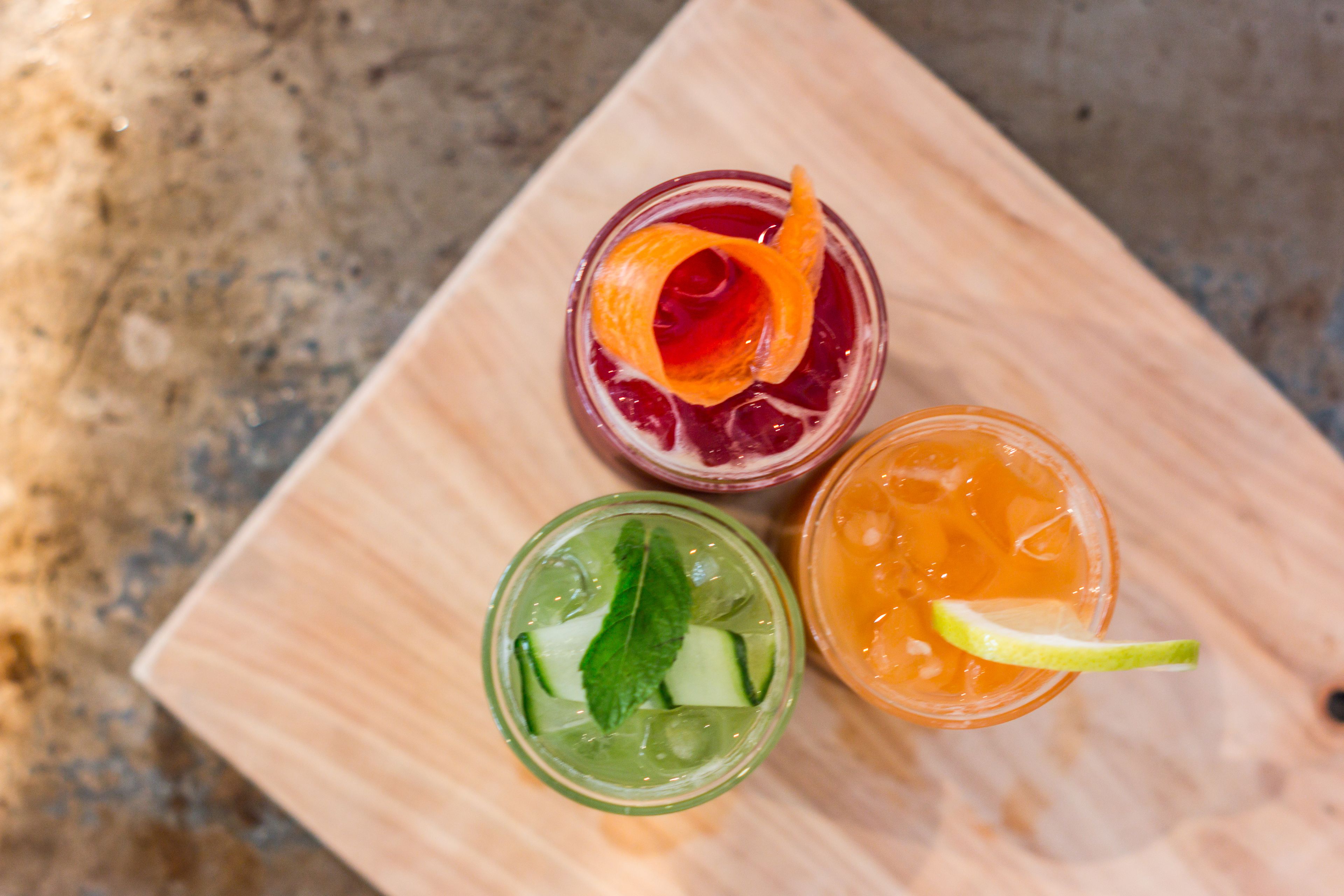 Three drinks on a wooden board.