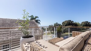 A balcony with wicker furniture, a potted plant, and a view of the ocean. - The Junction Boutique Hotel (Plettenberg Bay)