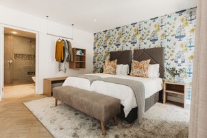 Un dormitorio moderno con una cama grande, un banco, un armario y una zona de ducha.