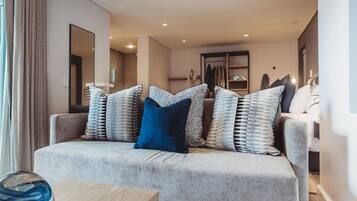 Un salón moderno con un sofá gris, cojines estampados, una mesa de centro de madera y un espejo grande en la pared.
