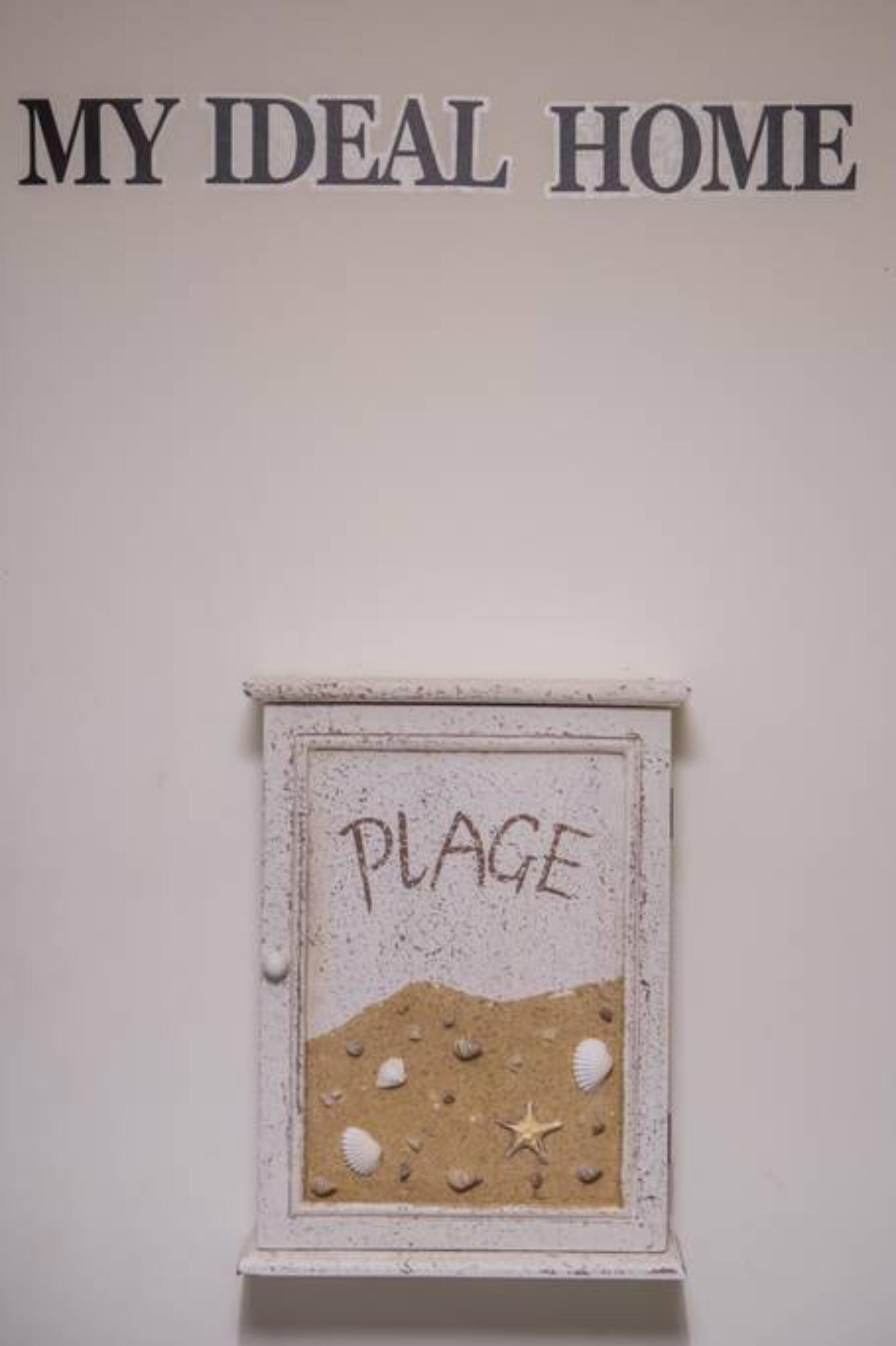 A wall with the text "MY IDEAL HOME" and a framed picture labeled "PLAGE" depicting a beach scene.