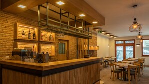 Un restaurant amb un taulell de fusta, parets de maó i llums penjants.