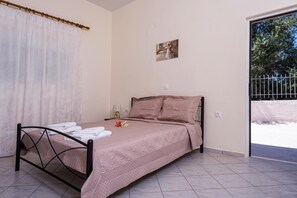 Ein Schlafzimmer mit Bett, einem Vorhangfenster, einem Bild an der Wand und einer Tür, die nach draußen führt.