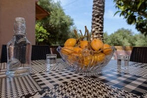 A table with a glass bowl of oranges and a clear bottle. - Palm Beach House (Kissamos)