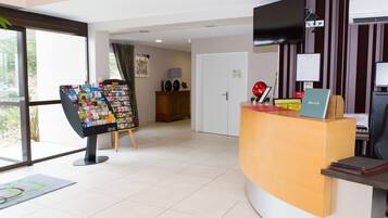 A reception area with a desk, a computer, and a magazine rack.