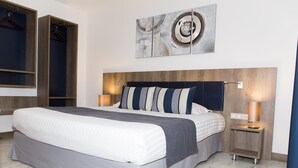 A modern hotel room with a large bed, a wooden headboard, two bedside tables with lamps, and a wall-mounted abstract art piece. - Hotel Restaurant Le Domaine des Oliviers (Pierrelatte)