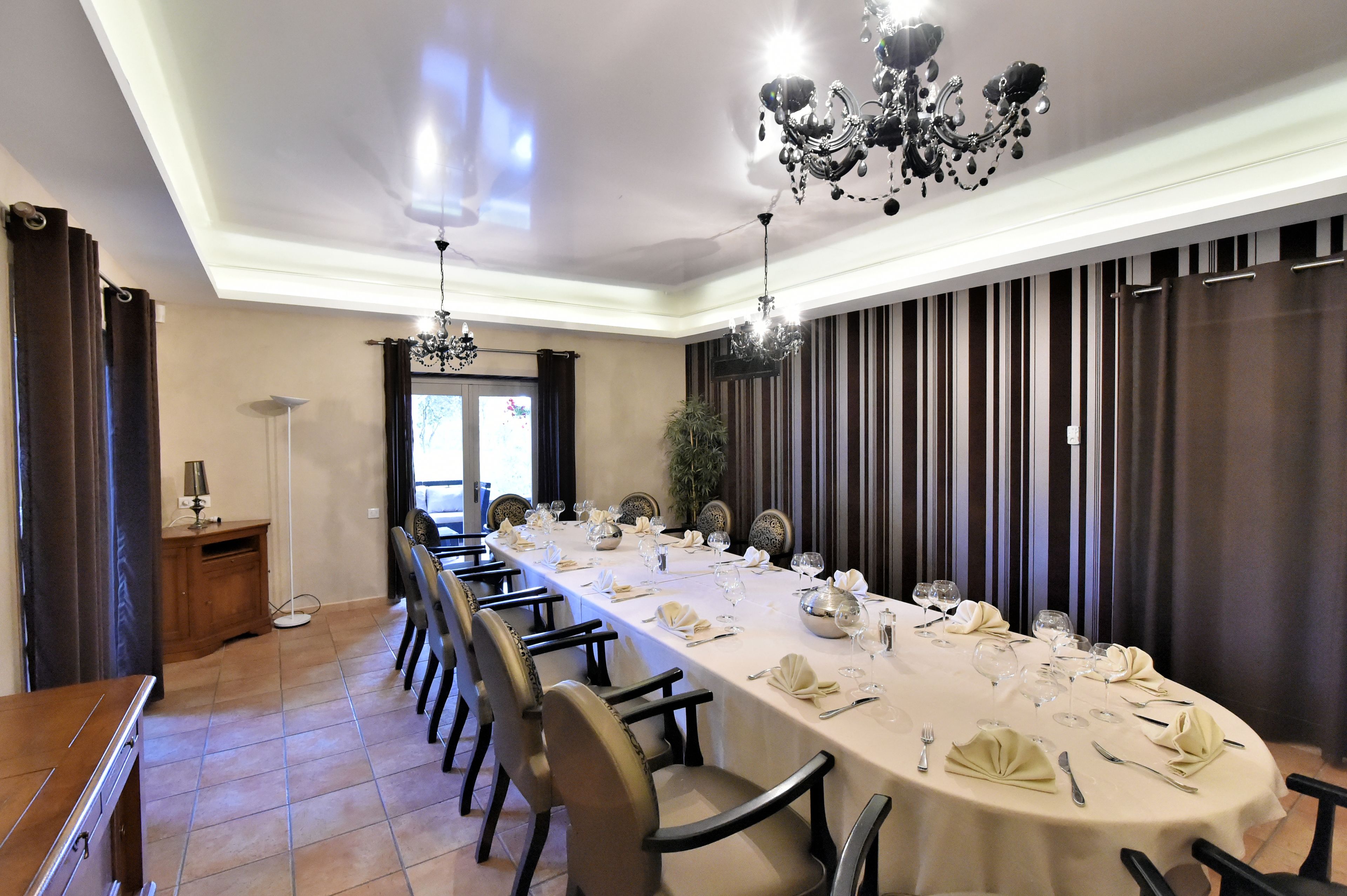 Una larga mesa de comedor dispuesta para una comida formal, con sillas y una araña.