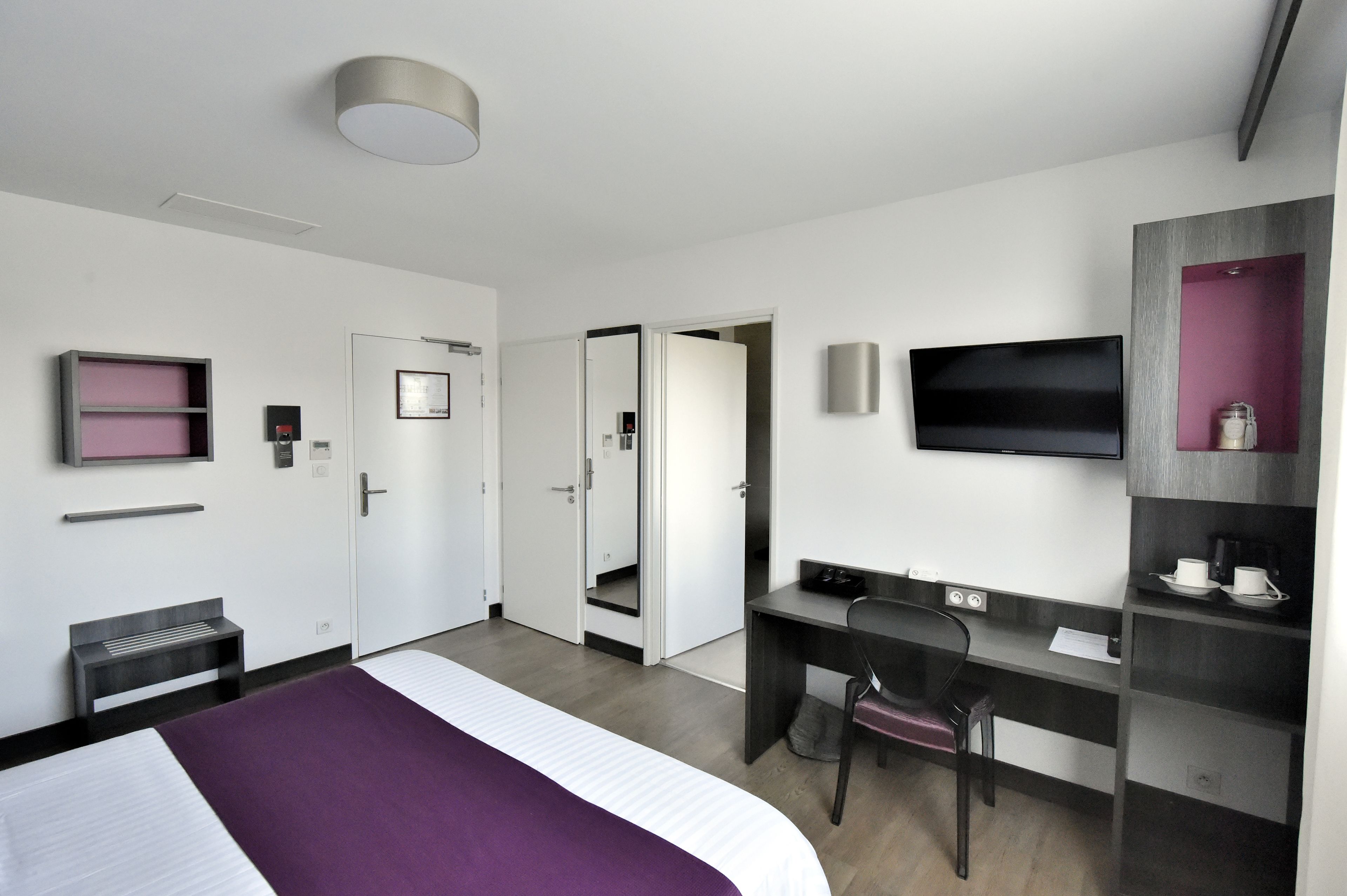Une chambre d’hôtel équipée d’un lit, d’un bureau, d’une chaise, d’une télévision et d’une armoire.