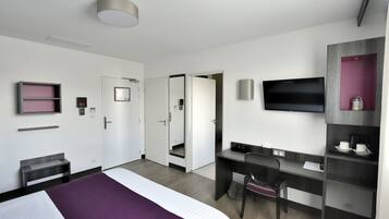 Une chambre d’hôtel équipée d’un lit, d’un bureau, d’une chaise, d’une télévision et d’une armoire.