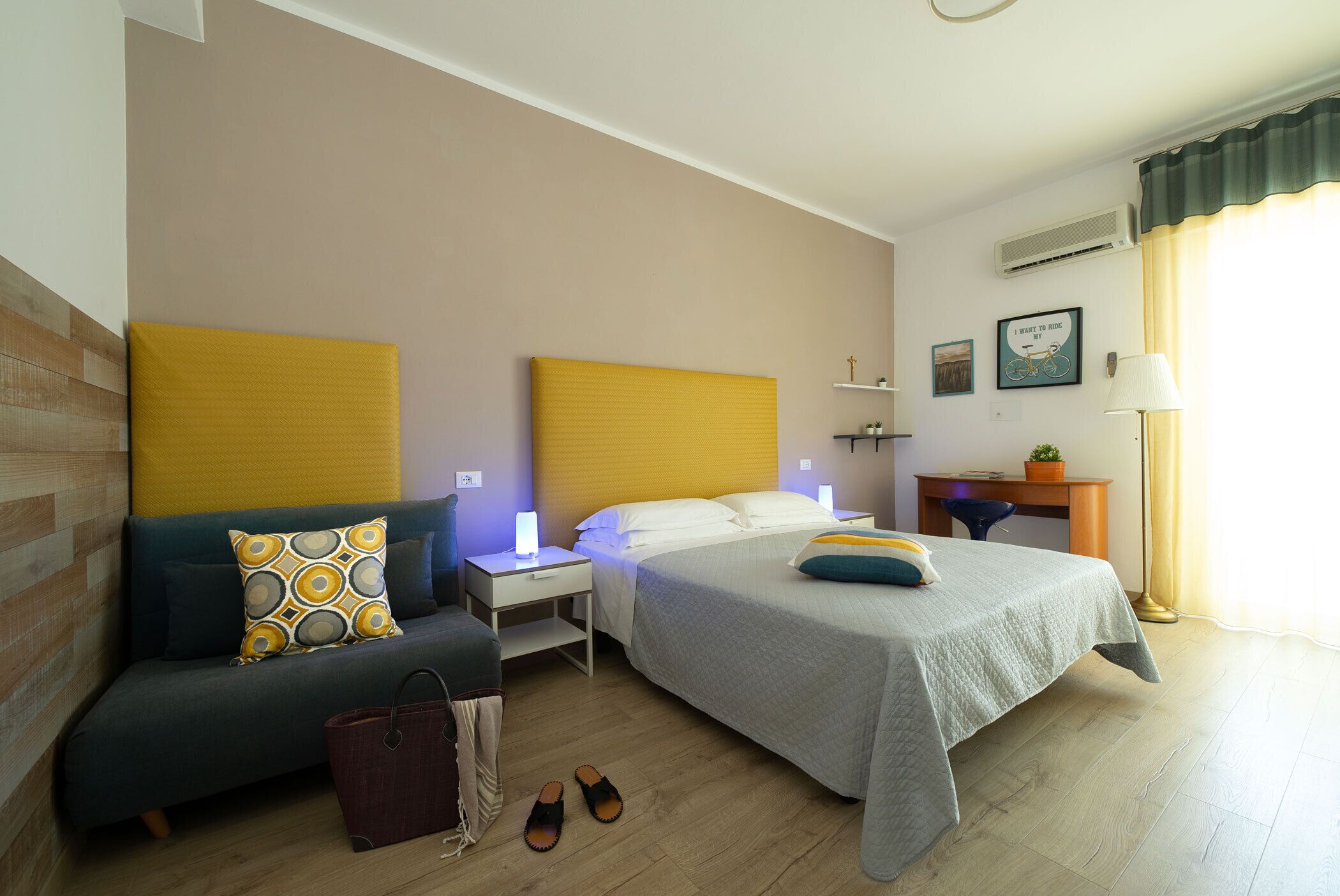 Habitación de hotel con dos camas, un sofá, un escritorio y una lámpara.