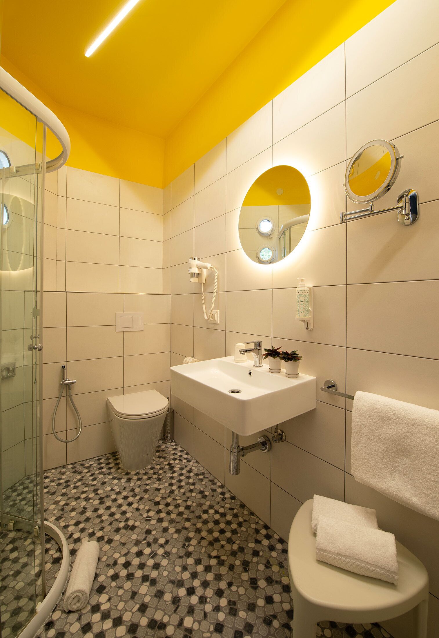 Un baño moderno con cabina de ducha de vidrio, inodoro, lavabo con espejo y toallero.