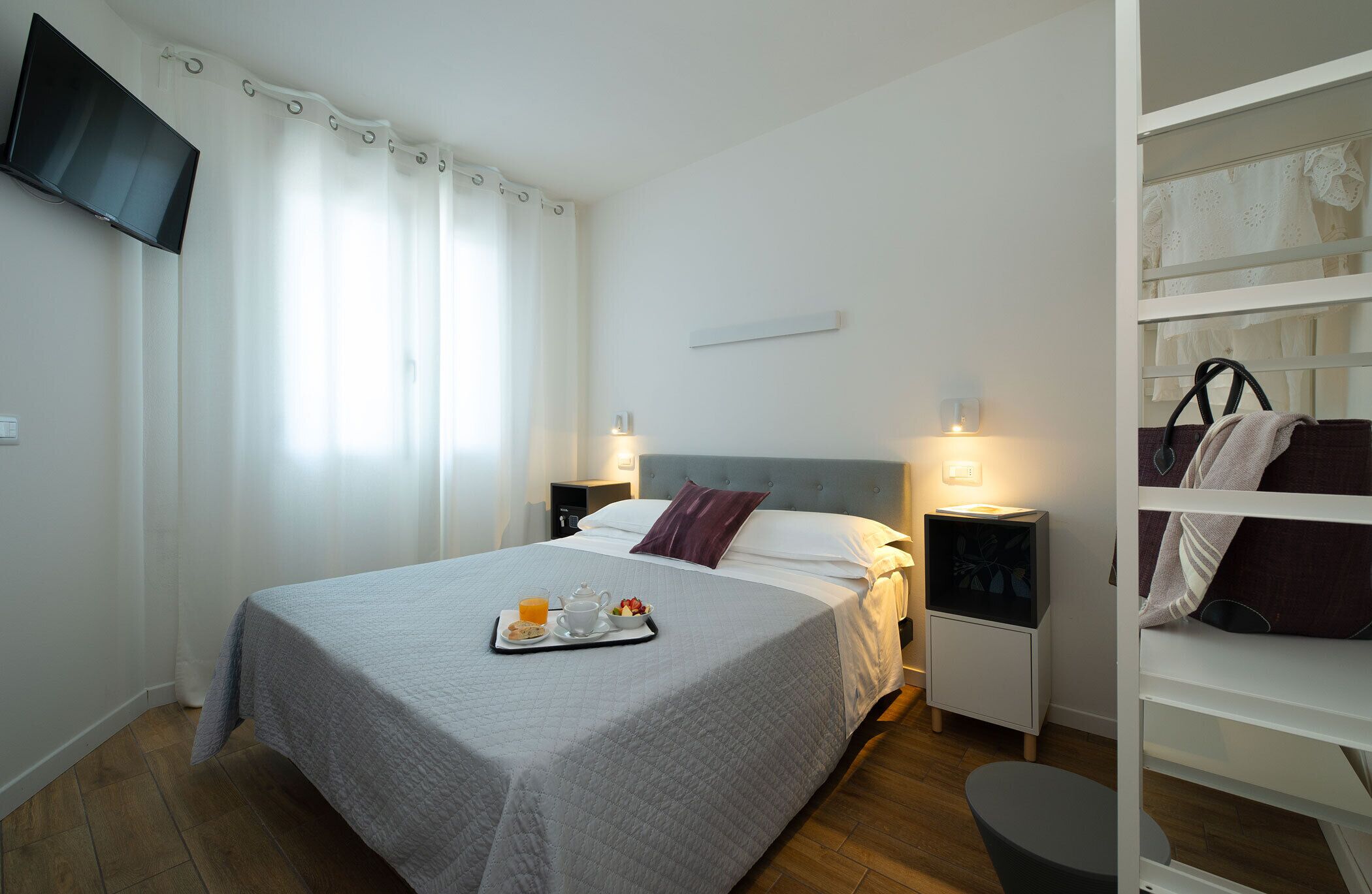 Une chambre d’hôtel bien rangée, avec un lit, des tables de chevet, une télévision et une armoire.