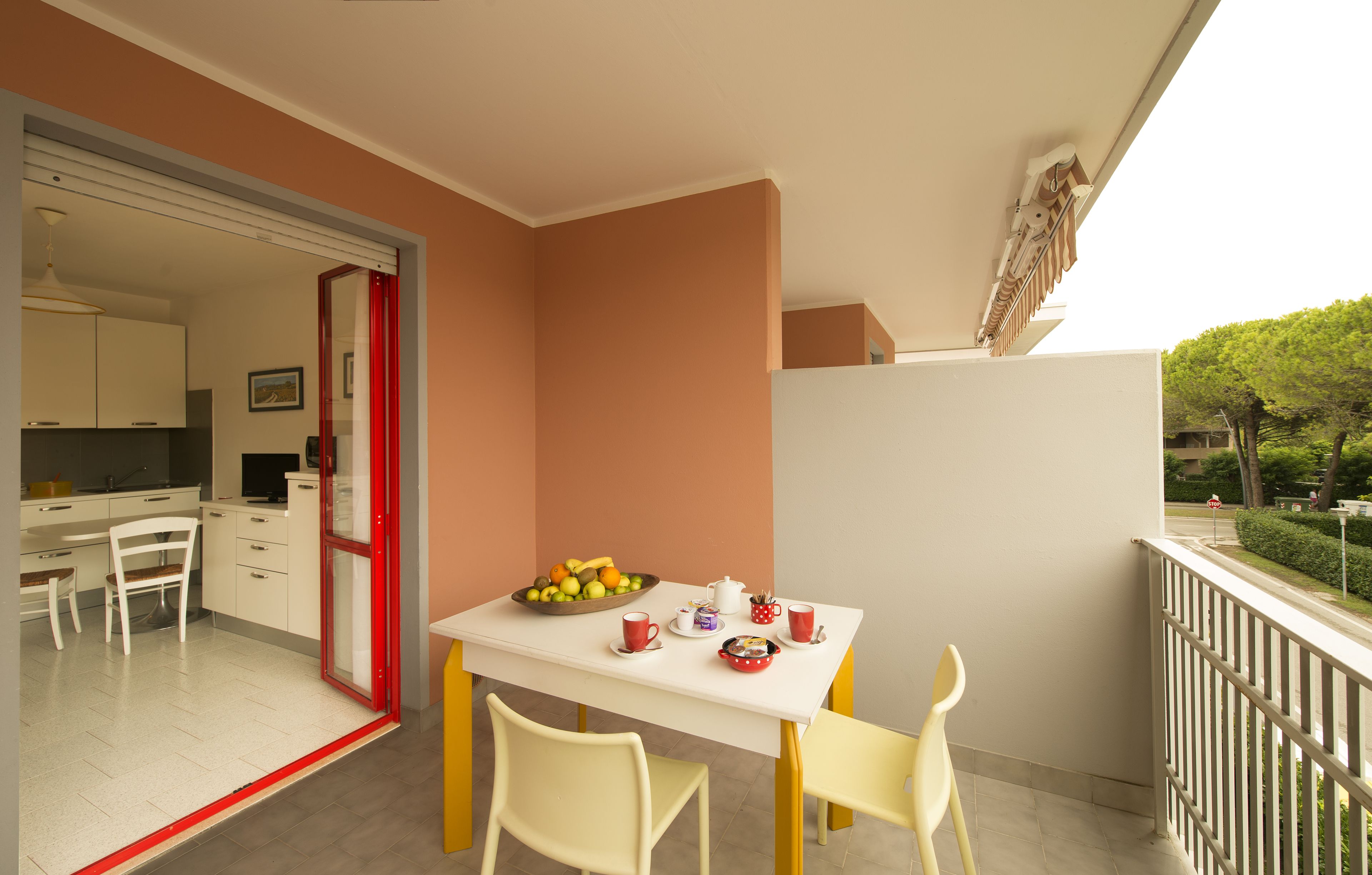 A balcony with a dining table, chairs, and a fruit bowl.