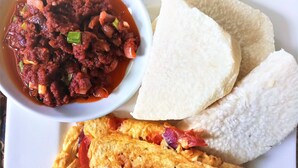 A plate with a bowl of stew, two pieces of white bread, and a fried egg. - City Travels Inn (Abuja)