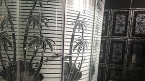 A bathroom with a toilet and a shower enclosure with a bamboo design. - City Travels Inn (Abuja)