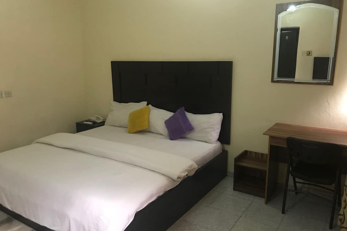 Ein Hotelzimmer mit Bett, Schreibtisch und Spiegel.