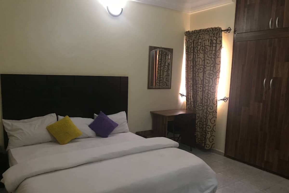 Ein Hotelzimmer mit einem Bett, einem Schreibtisch, einem Kleiderschrank und einem Vorhang.