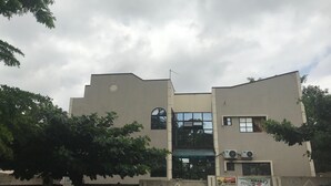 A modern building with a flat roof, large windows, and two air conditioning units on the facade. - City Travels Inn (Abuja)