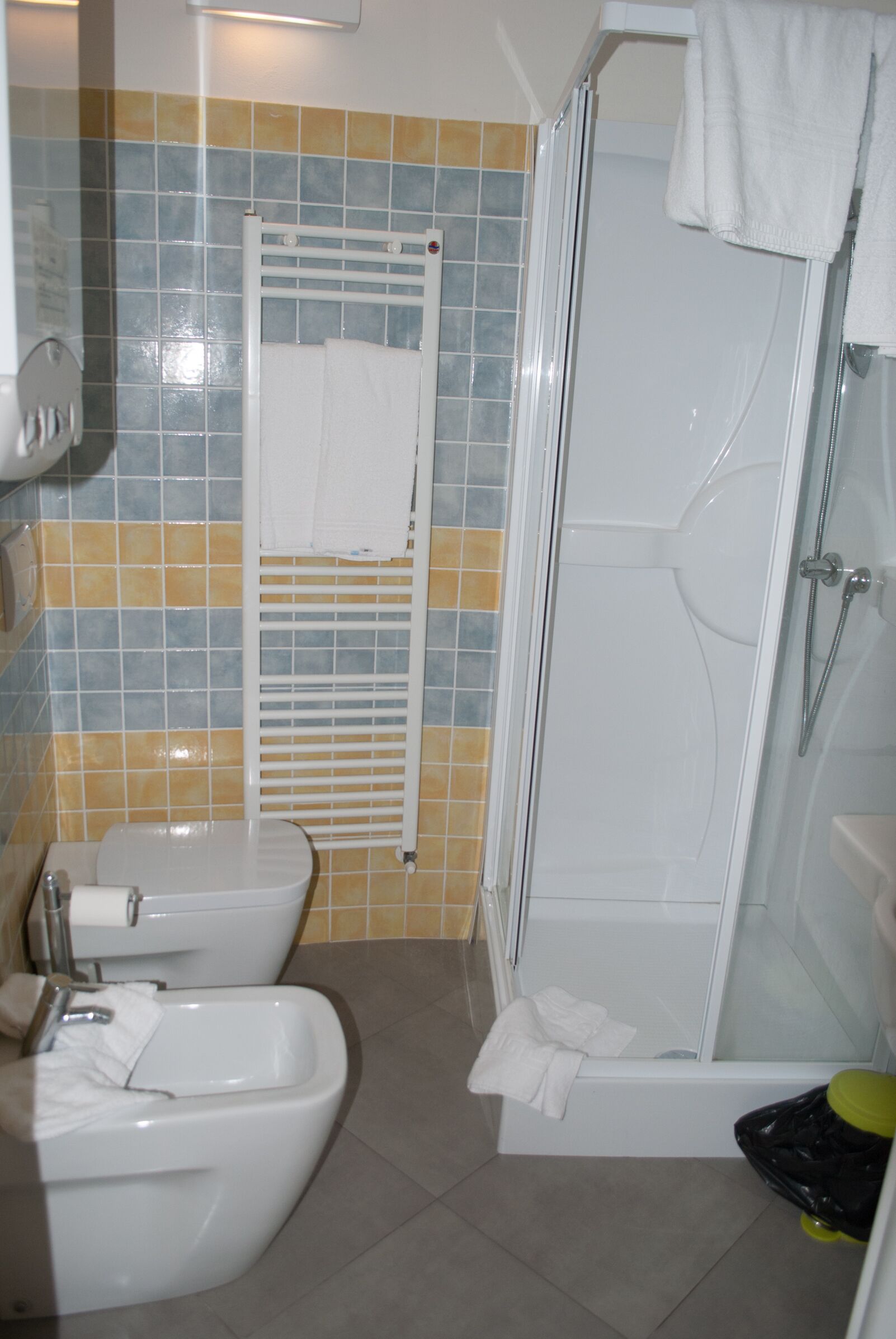 Un bagno con doccia, WC, bidet e pareti rivestite di piastrelle.