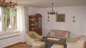 Un soggiorno con divano, tavolino, mobile e lampadario.