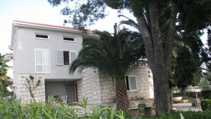 Un edificio a due piani con facciata in pietra, persiane bianche e tetto in tegole.