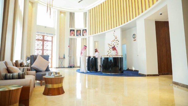 Een ruime lobby met een gebogen plafond, een receptiebalie en een zithoek met banken en een salontafel.