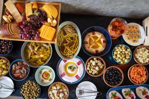 Una variedad de alimentos, incluyendo quesos, frutas, verduras y platos de pasta dispuestos sobre una mesa.