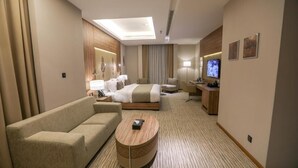Een hotelkamer met een bed, een bank, een televisie en een bureau.