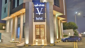 Een hotelentree met een opvallend ‘V’-logo en Arabische tekst.