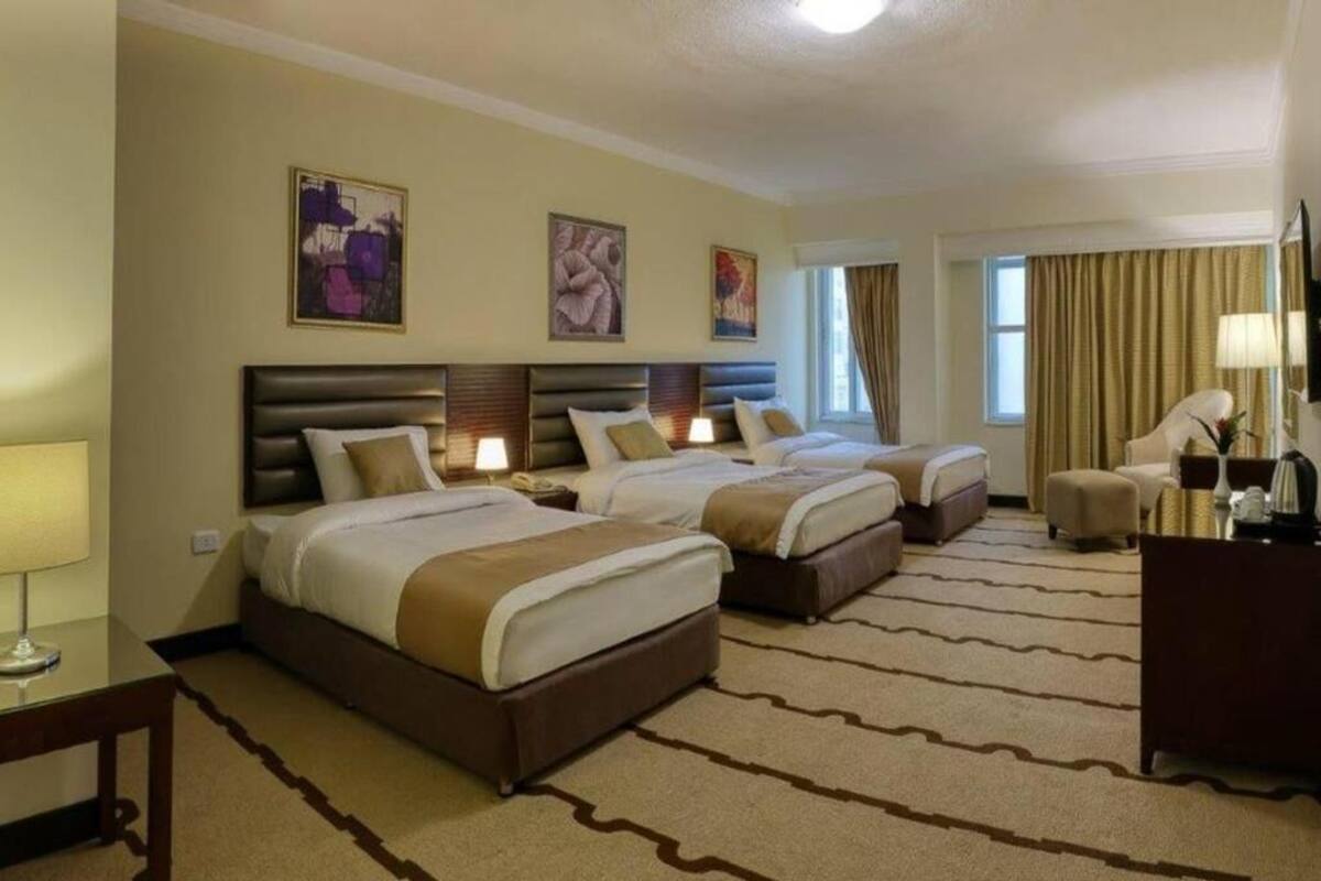 Een hotelkamer met drie bedden, een bureau en een stoel.