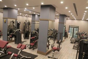 A gym with various exercise machines, mirrors, and a treadmill. - Sandy Palace Hotel (Amman)